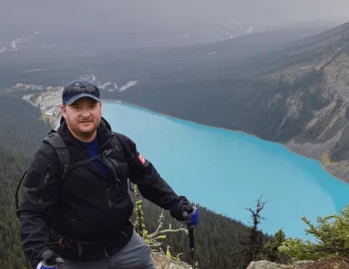 Man wearing hoodie on cliff overlooking lake