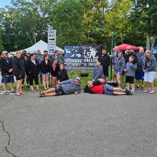 Group of people in outdoor setting with trees and tent